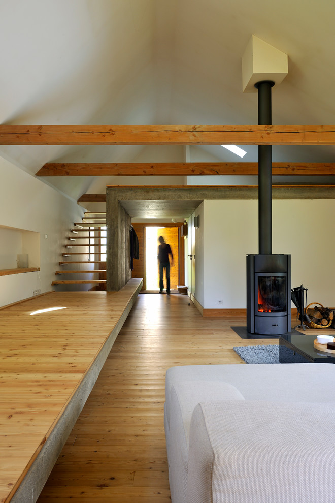 Imagen de salón para visitas abierto industrial grande con paredes blancas, suelo de madera en tonos medios y marco de chimenea de metal