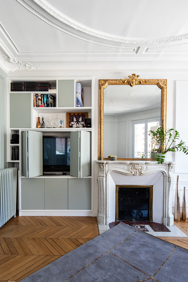 Idée de décoration pour un grand salon tradition avec une bibliothèque ou un coin lecture, un mur blanc, une cheminée standard, un manteau de cheminée en pierre, un téléviseur dissimulé, un sol en bois brun et un sol marron.