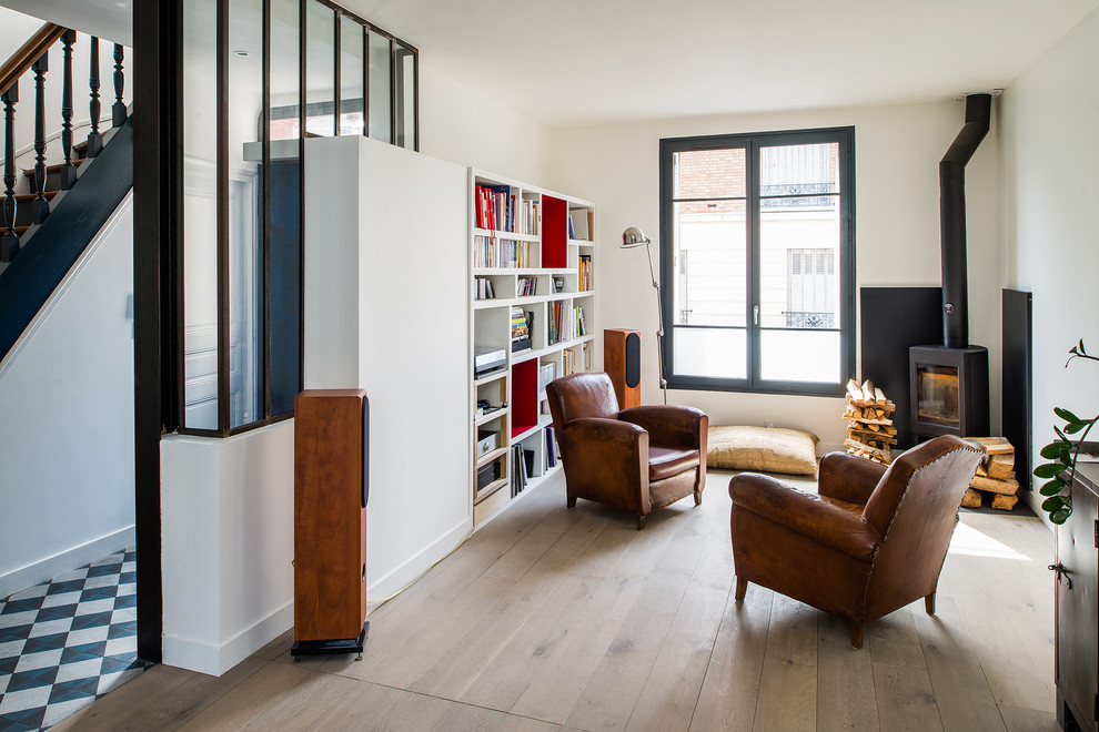Living room library - mid-sized industrial open concept light wood floor living room library idea in Paris with white walls, a wood stove and no tv