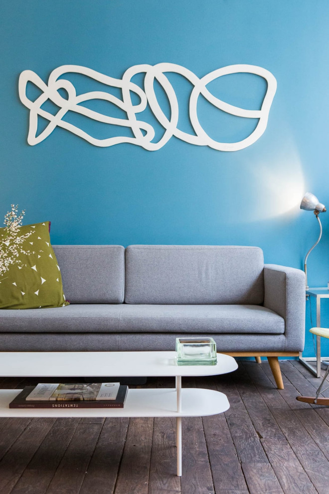 Kleines, Fernseherloses, Offenes Modernes Wohnzimmer mit dunklem Holzboden, braunem Boden und blauer Wandfarbe in Paris
