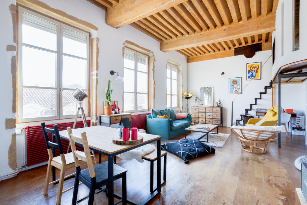 Example of an eclectic open concept medium tone wood floor, brown floor and exposed beam living room design in Lyon with white walls