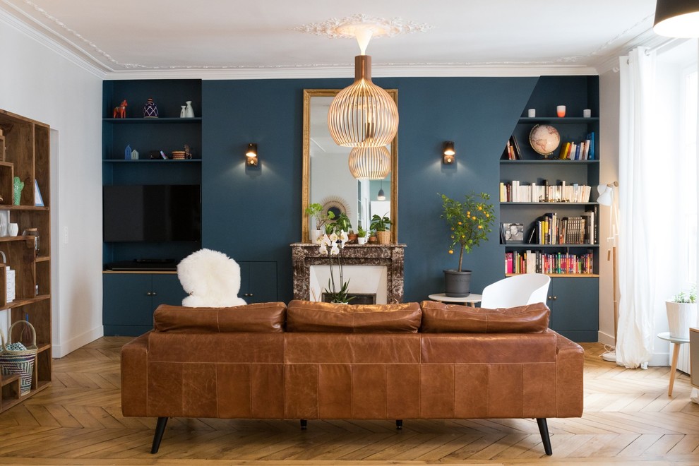 Foto di un grande soggiorno minimal aperto con libreria, pareti blu, pavimento in legno massello medio, camino classico, cornice del camino in metallo e pavimento marrone