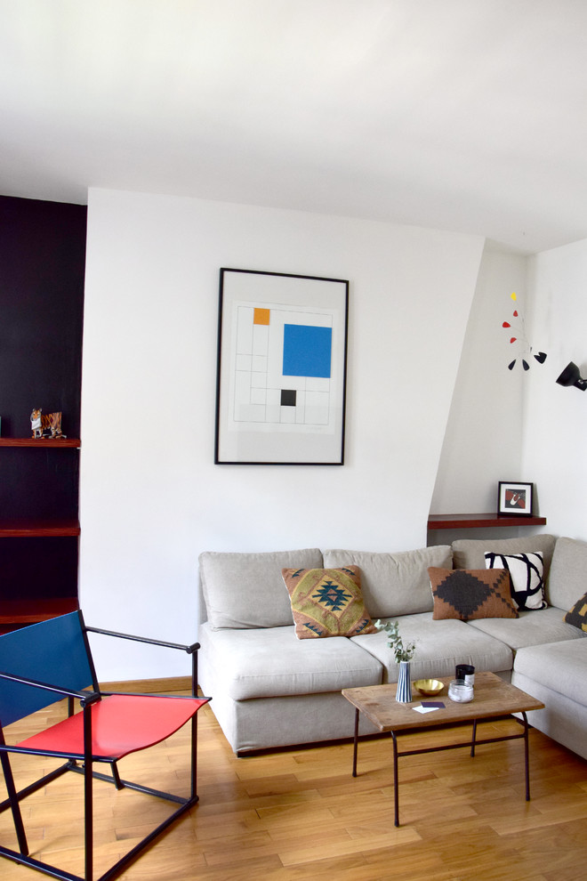 Modern inredning av ett litet separat vardagsrum, med vita väggar, mellanmörkt trägolv och en väggmonterad TV