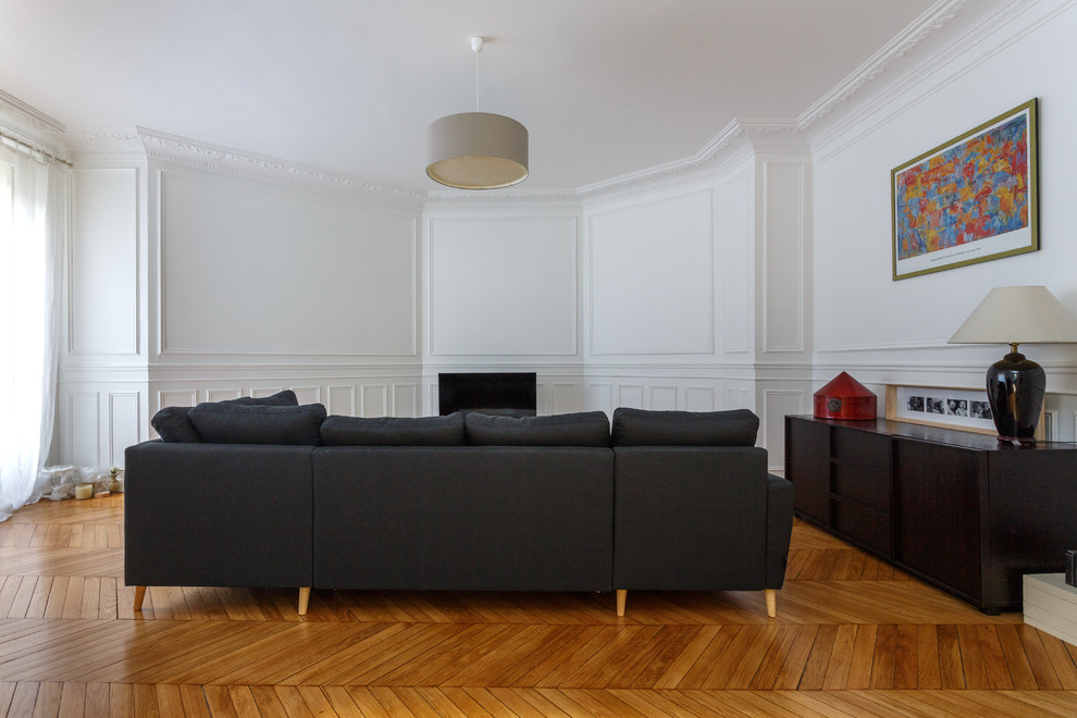На фото: большая открытая гостиная комната в скандинавском стиле с белыми стенами, паркетным полом среднего тона, отдельно стоящим телевизором и коричневым полом без камина