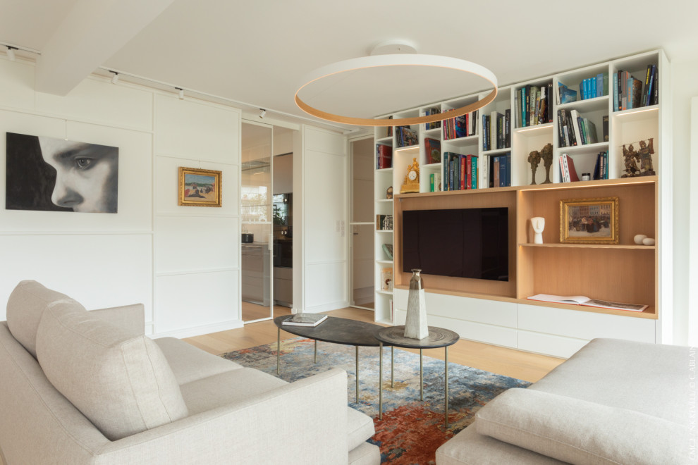 Ejemplo de salón abierto actual de tamaño medio sin chimenea con paredes blancas, suelo de madera clara y pared multimedia