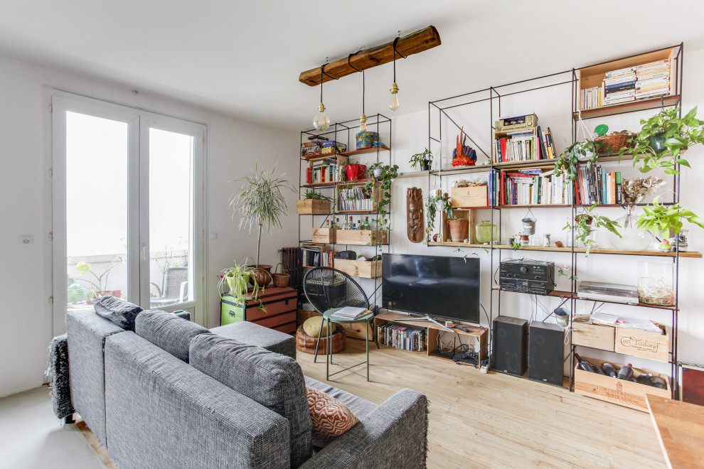 Offenes Stilmix Wohnzimmer mit weißer Wandfarbe, hellem Holzboden, freistehendem TV und beigem Boden in Toulouse