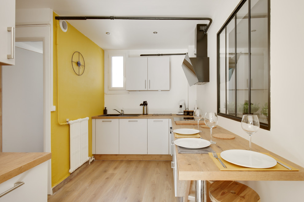 Idee per un soggiorno industriale di medie dimensioni e aperto con pareti gialle, pavimento in laminato, nessun camino, TV a parete e pavimento marrone