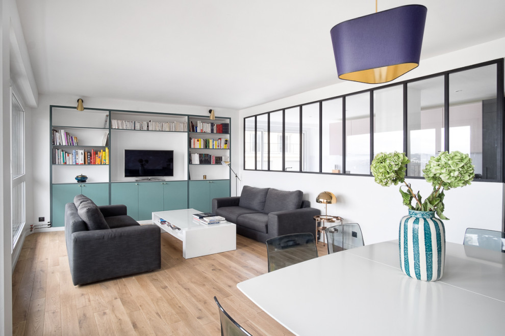 Offenes Modernes Wohnzimmer mit weißer Wandfarbe, hellem Holzboden, freistehendem TV und beigem Boden in Paris