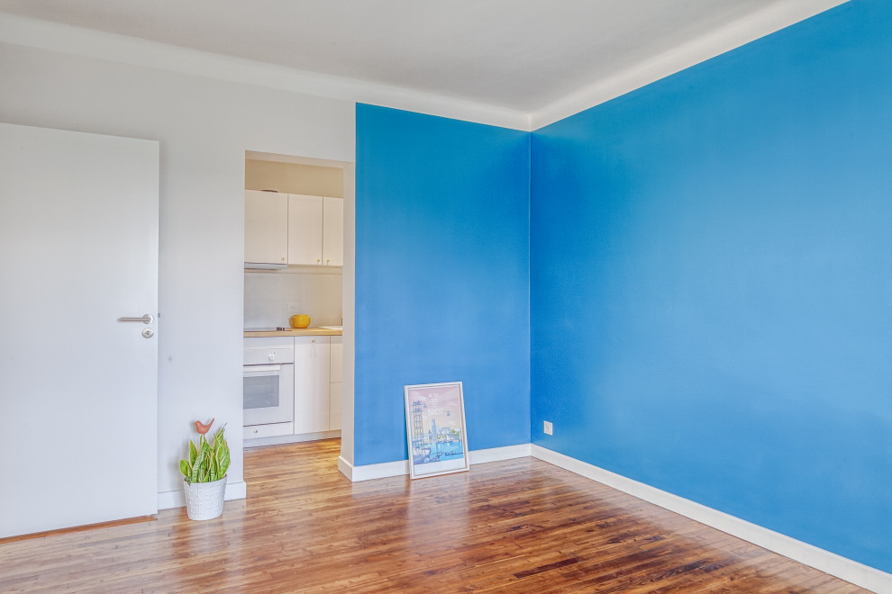 Réalisation d'un salon minimaliste de taille moyenne et fermé avec un mur bleu, sol en stratifié et un sol marron.