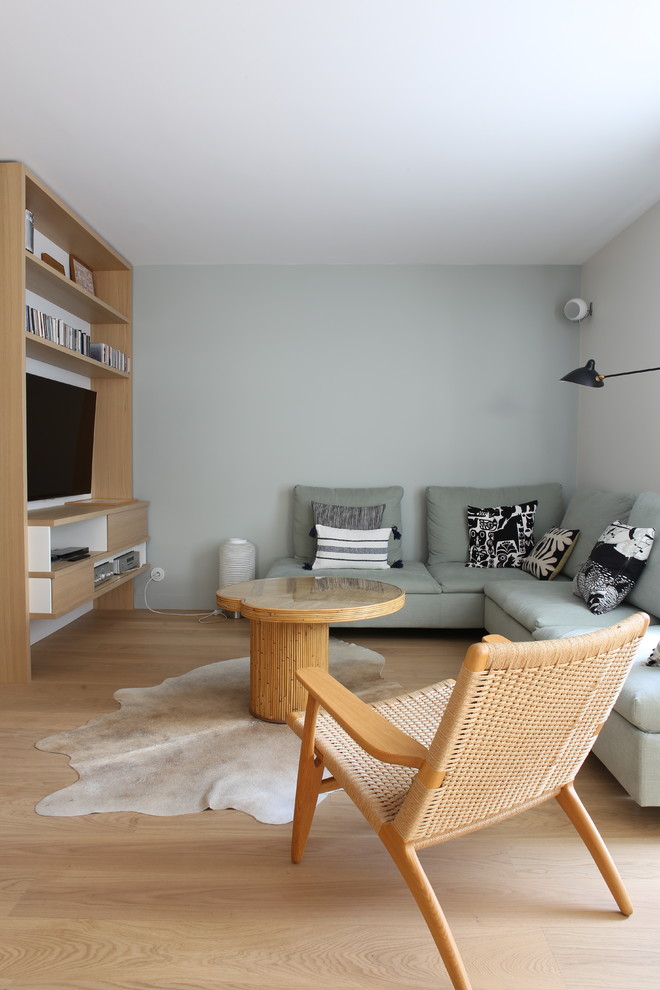 Exemple d'un salon tendance de taille moyenne et ouvert avec une bibliothèque ou un coin lecture, un mur blanc, parquet clair, un téléviseur fixé au mur et un sol beige.