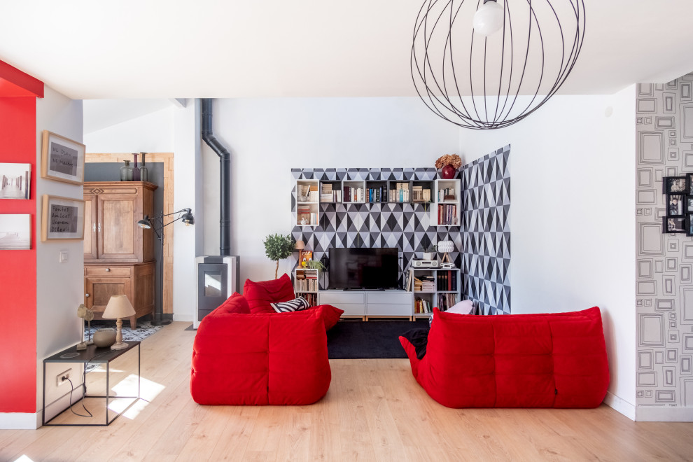 Стильный дизайн: открытая гостиная комната среднего размера в современном стиле с отдельно стоящим телевизором, белыми стенами, печью-буржуйкой, фасадом камина из металла, бежевым полом и обоями на стенах - последний тренд