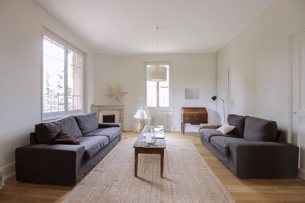 Idée de décoration pour un grand salon nordique fermé avec un mur blanc, parquet clair, une cheminée standard, un manteau de cheminée en pierre et un sol beige.