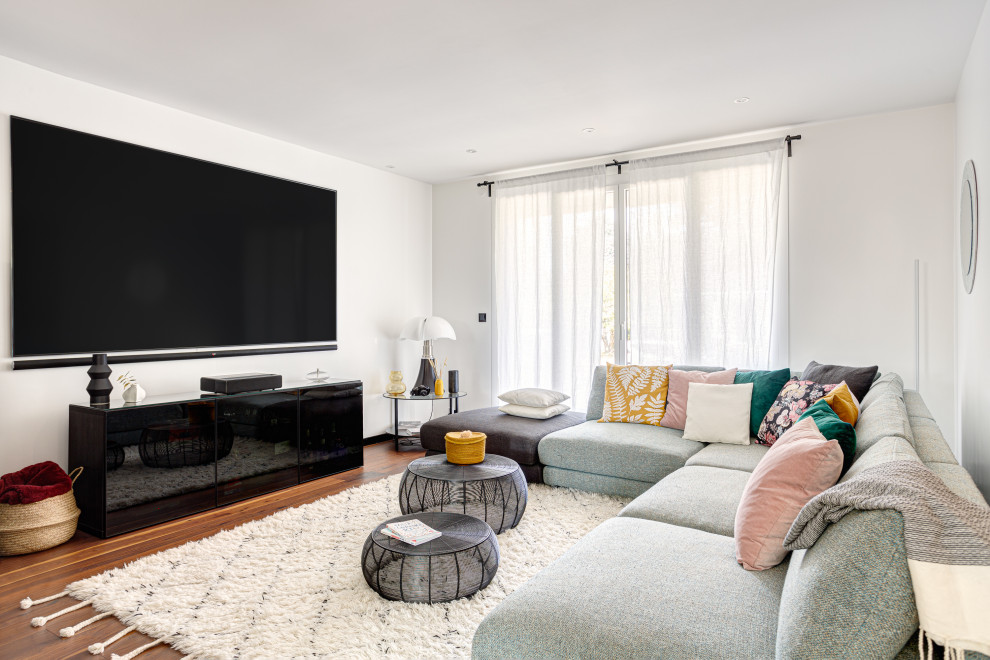 Идея дизайна: гостиная комната в современном стиле с белыми стенами, темным паркетным полом, телевизором на стене и коричневым полом