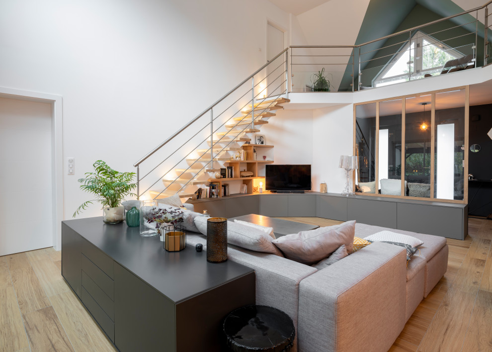 Ispirazione per un grande soggiorno design aperto con pareti bianche, parquet chiaro, TV autoportante e pavimento beige