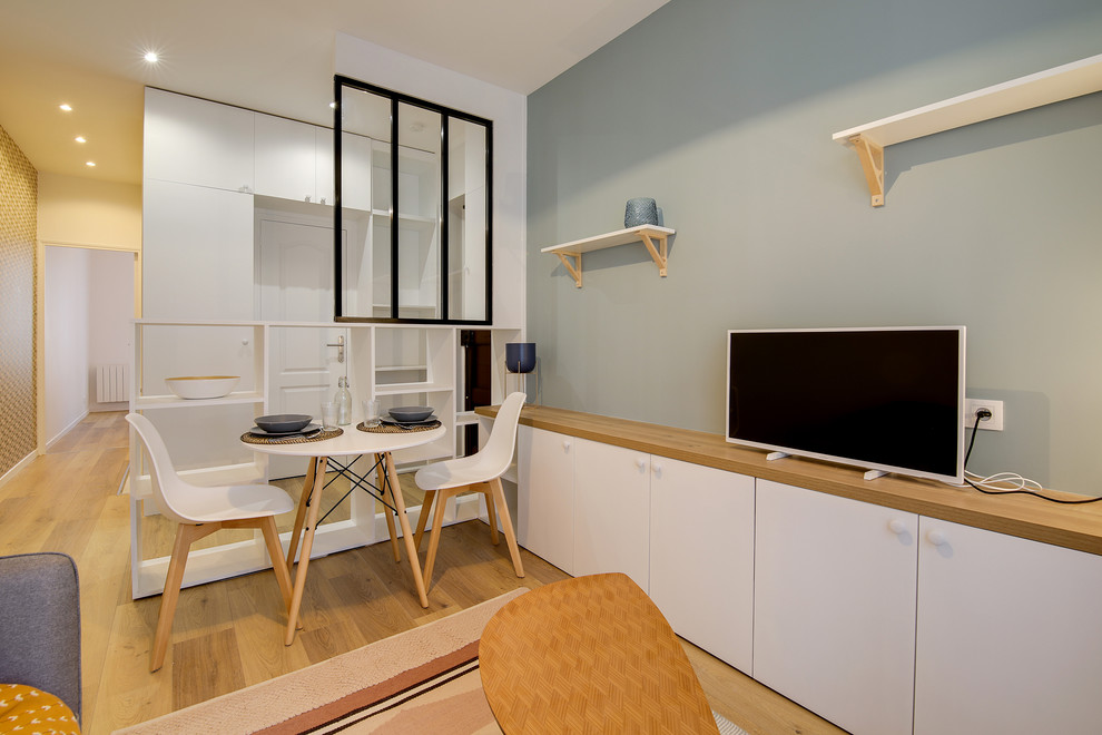 Aménagement d'un petit salon scandinave ouvert avec un mur bleu, sol en stratifié et un téléviseur indépendant.