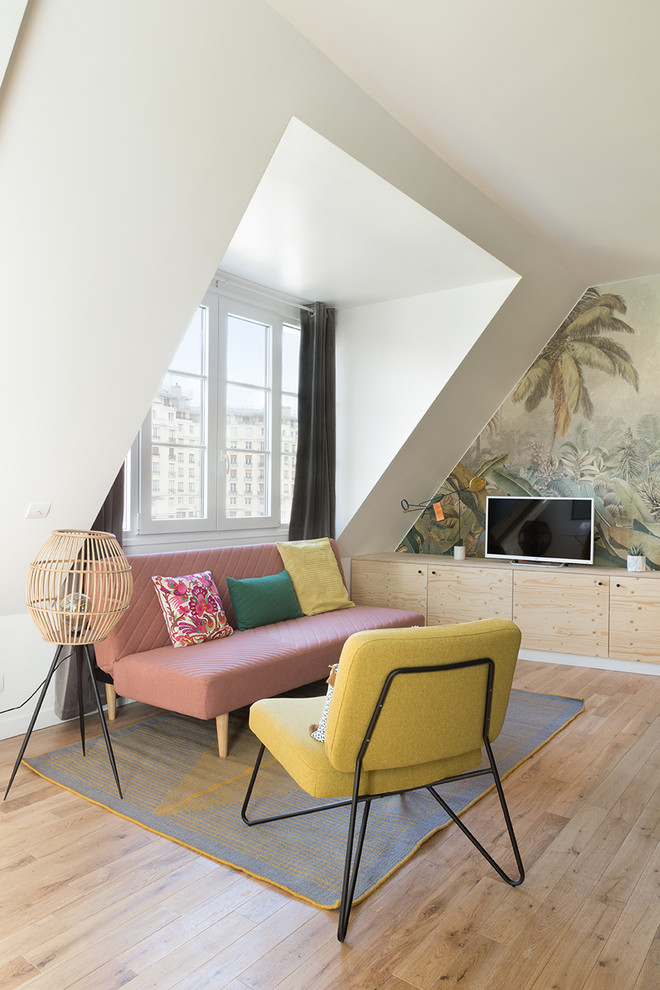 Kleines Wohnzimmer ohne Kamin mit hellem Holzboden, bunten Wänden und freistehendem TV in Paris