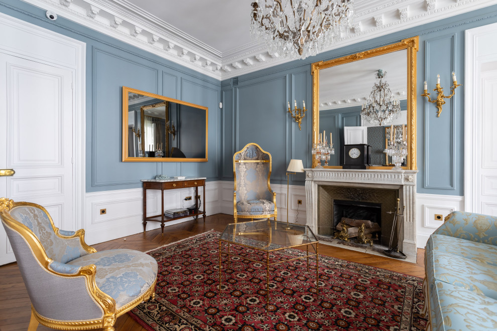 パリにあるラグジュアリーな広いヴィクトリアン調のおしゃれな独立型リビング (青い壁、濃色無垢フローリング、標準型暖炉、壁掛け型テレビ、茶色い床、羽目板の壁) の写真