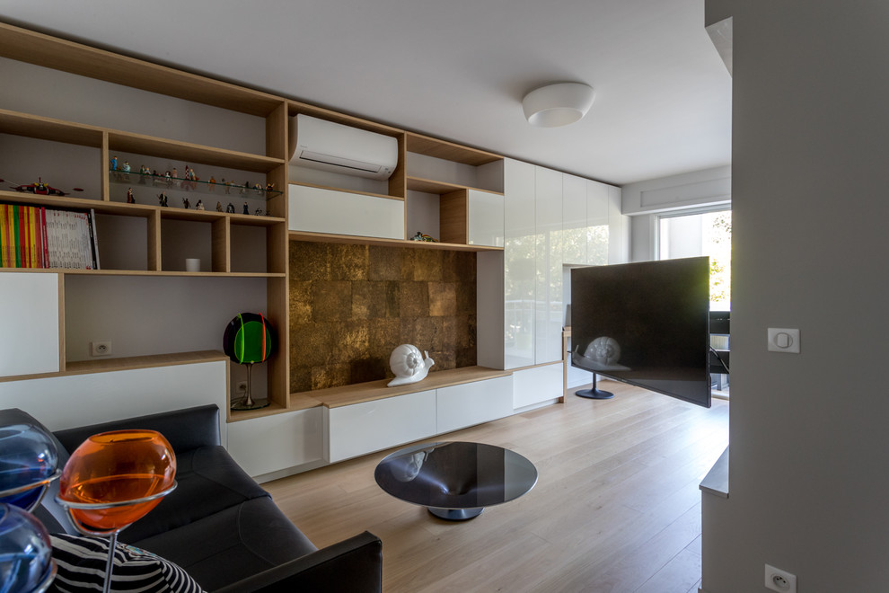 На фото: открытая гостиная комната среднего размера в современном стиле с с книжными шкафами и полками, белыми стенами, светлым паркетным полом и скрытым телевизором