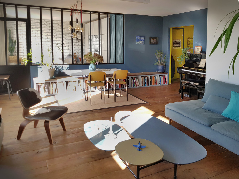 Ispirazione per un soggiorno minimalista di medie dimensioni e aperto con libreria, pareti blu, parquet chiaro, nessun camino, nessuna TV e pavimento marrone
