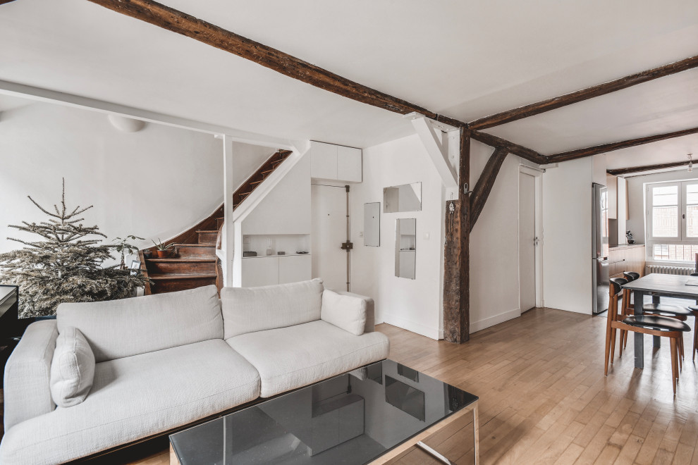 Aménagement d'un salon contemporain de taille moyenne et ouvert avec un mur blanc, parquet clair, aucune cheminée, aucun téléviseur, un sol marron, poutres apparentes et un escalier.