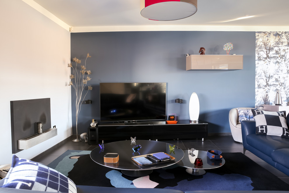На фото: большая открытая гостиная комната в современном стиле с серыми стенами, полом из керамической плитки, подвесным камином, фасадом камина из металла, отдельно стоящим телевизором и серым полом с