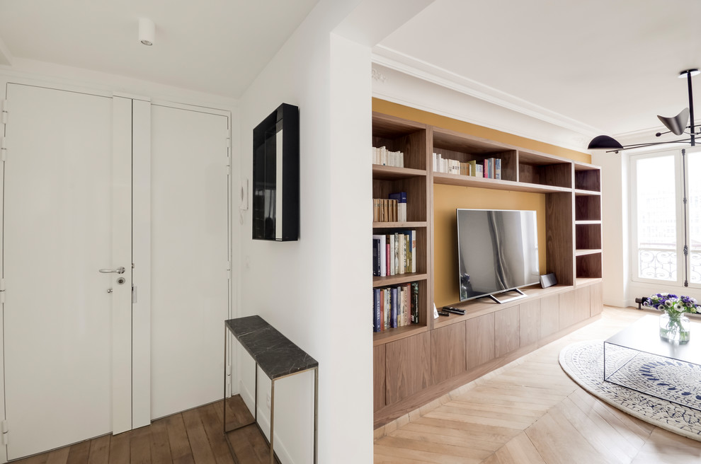 Foto de biblioteca en casa abierta contemporánea de tamaño medio sin chimenea con paredes amarillas, suelo de madera clara, televisor colgado en la pared y suelo marrón