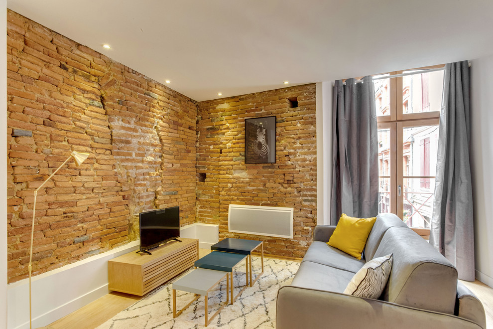 Esempio di un piccolo soggiorno contemporaneo aperto con pareti arancioni, parquet chiaro e TV autoportante
