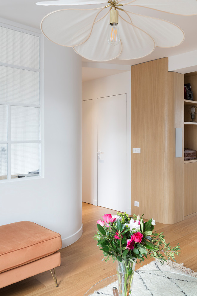 На фото: открытая гостиная комната среднего размера в современном стиле с с книжными шкафами и полками, белыми стенами, светлым паркетным полом и мультимедийным центром