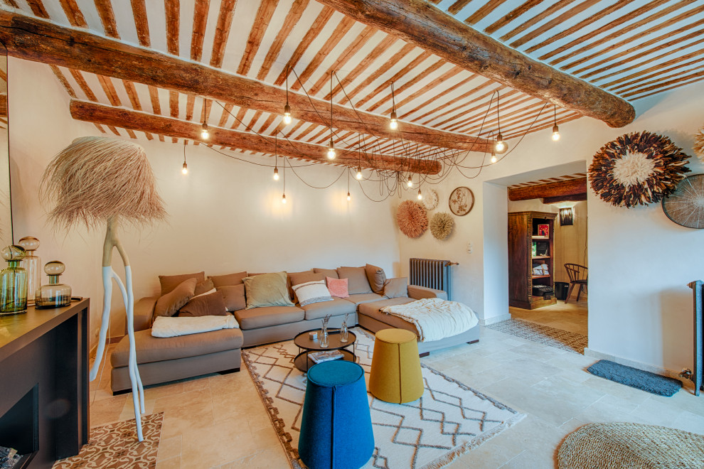 Immagine di un soggiorno mediterraneo con pareti bianche, pavimento beige e travi a vista