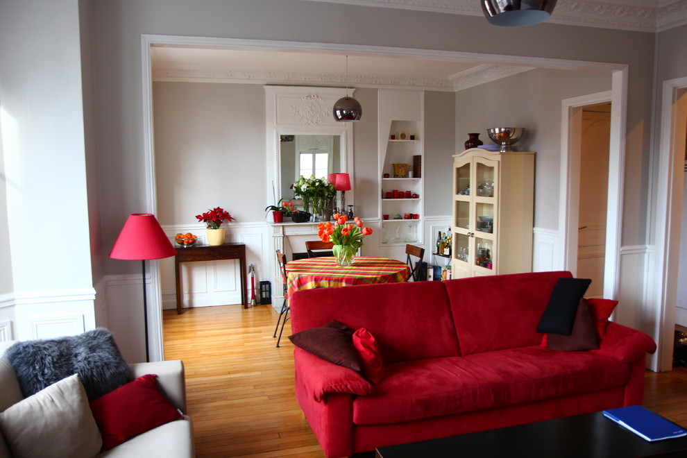 Mittelgroßes, Fernseherloses, Offenes Klassisches Wohnzimmer mit grauer Wandfarbe, hellem Holzboden, Kamin, verputzter Kaminumrandung und braunem Boden in Paris
