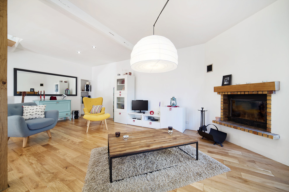 Diseño de salón abierto bohemio grande con paredes blancas, suelo de madera clara, chimenea de esquina, marco de chimenea de yeso y televisor independiente