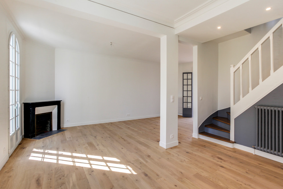 Foto de salón abierto clásico grande con paredes blancas, suelo de madera clara, chimenea de esquina y suelo negro