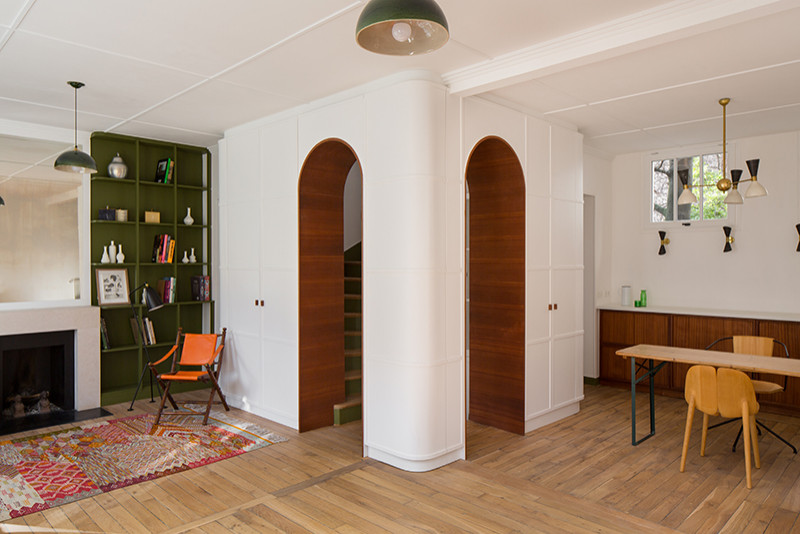 Mittelgroße Moderne Bibliothek mit grüner Wandfarbe, hellem Holzboden, Kamin, Kaminumrandung aus Stein, Holzdielendecke und vertäfelten Wänden in Paris