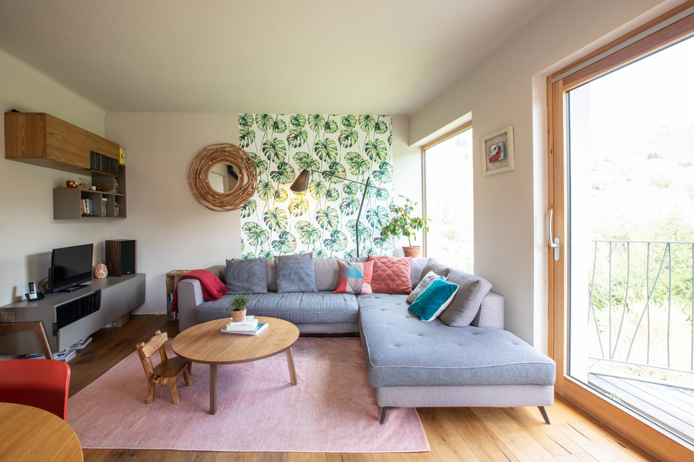 Immagine di un grande soggiorno minimalista aperto con pareti beige, parquet scuro, stufa a legna, TV autoportante, pavimento marrone, cornice del camino in metallo e carta da parati