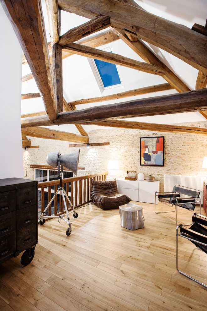 Example of a large country loft-style light wood floor living room library design in Paris with white walls