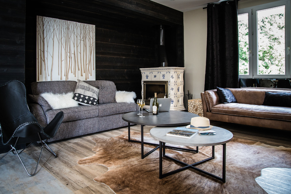 This is an example of a rustic living room in Dijon with black walls, light hardwood flooring, a corner fireplace, a tiled fireplace surround and beige floors.