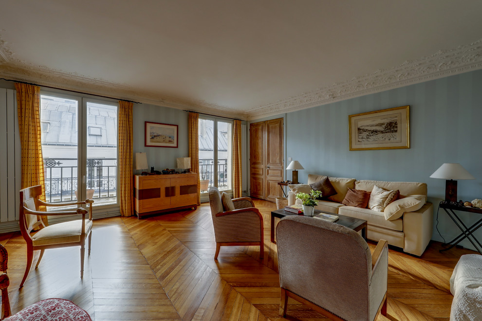 This is an example of a large eclectic enclosed living room in Paris with blue walls, light hardwood flooring, no tv, brown floors, a standard fireplace and a stone fireplace surround.