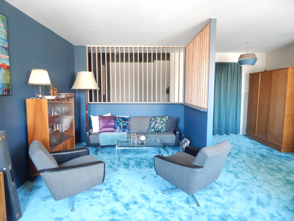 Large mid-century modern open concept carpeted and blue floor living room photo in Lyon with blue walls