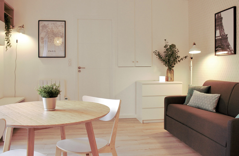Modelo de salón abierto escandinavo pequeño con paredes blancas, suelo laminado y televisor independiente