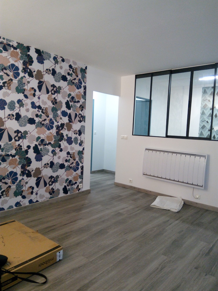 Cette image montre un salon minimaliste de taille moyenne et ouvert avec un mur multicolore, parquet foncé, aucune cheminée, un téléviseur fixé au mur et un sol gris.