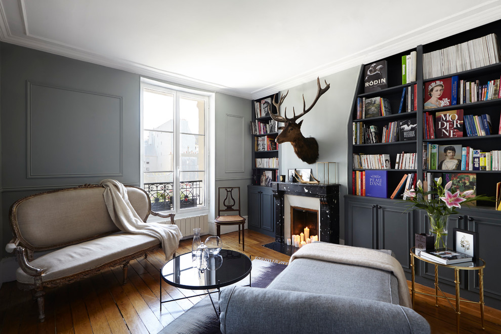 Mittelgroße, Fernseherlose, Abgetrennte Stilmix Bibliothek mit grauer Wandfarbe, Kamin und braunem Holzboden in Paris