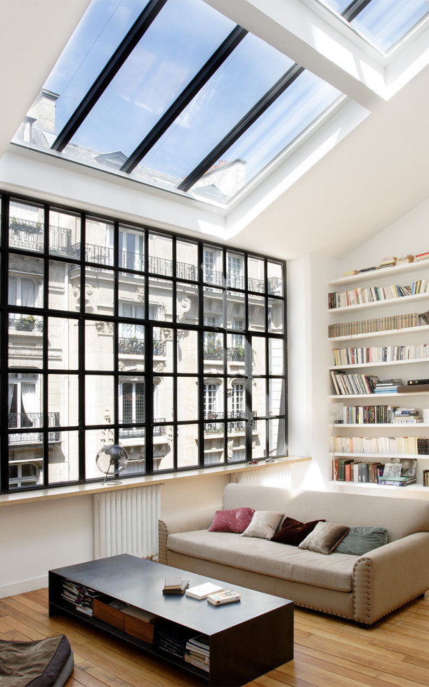 Idées déco pour un salon contemporain ouvert avec une bibliothèque ou un coin lecture, un mur blanc et parquet clair.