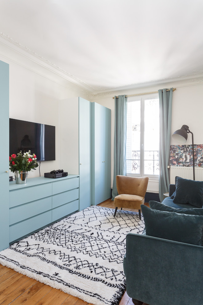 Пример оригинального дизайна: парадная, изолированная гостиная комната в современном стиле с белыми стенами, паркетным полом среднего тона, телевизором на стене, коричневым полом и синими шторами