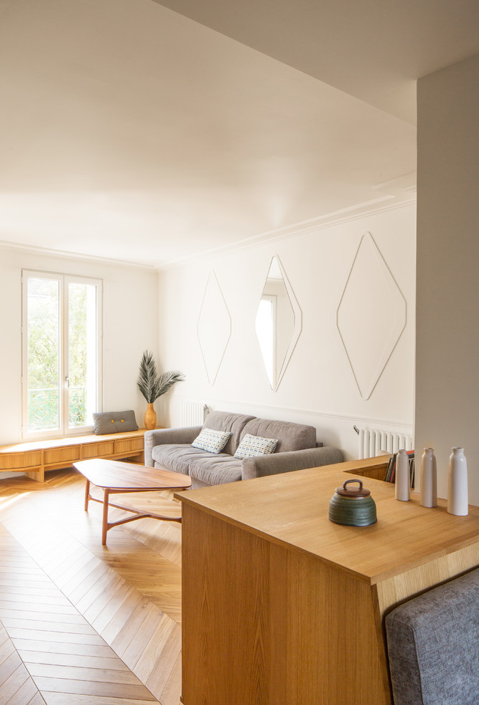 Immagine di un piccolo soggiorno design aperto con pareti bianche, parquet chiaro e pavimento beige