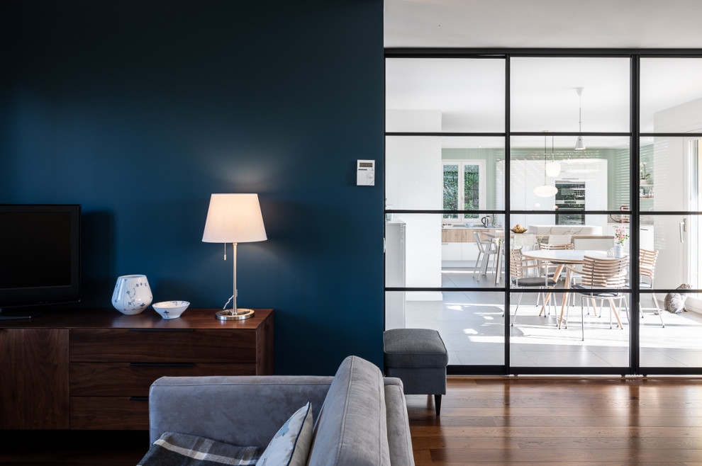 Nordisches Wohnzimmer ohne Kamin mit blauer Wandfarbe, braunem Holzboden und braunem Boden in Lyon