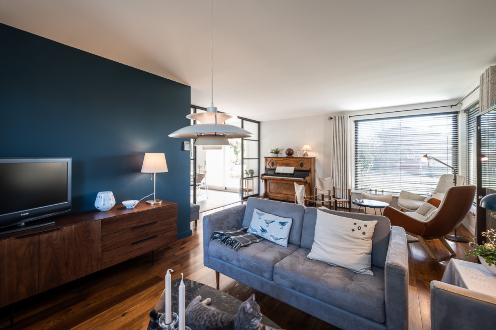 Стильный дизайн: гостиная комната в скандинавском стиле с синими стенами, паркетным полом среднего тона и коричневым полом без камина - последний тренд