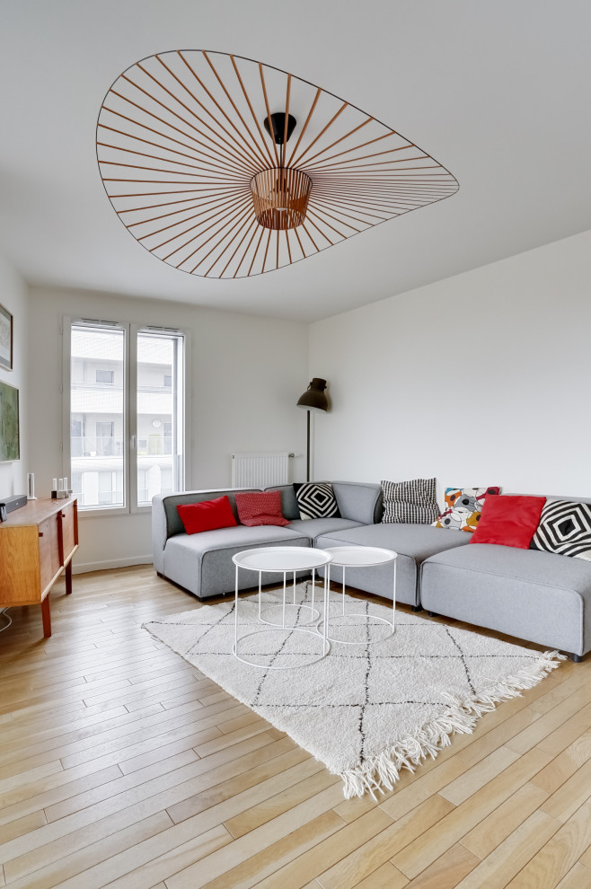 Стильный дизайн: открытая гостиная комната среднего размера в скандинавском стиле с белыми стенами, полом из ламината и телевизором на стене - последний тренд