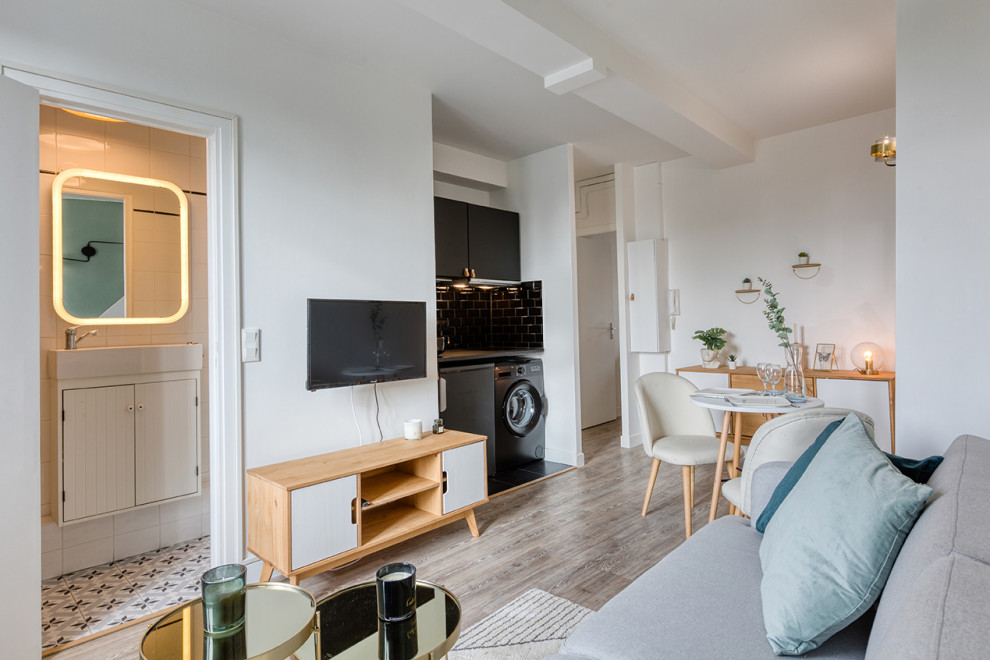 Стильный дизайн: маленькая открытая гостиная комната в скандинавском стиле с белыми стенами, телевизором на стене и серым полом для на участке и в саду - последний тренд