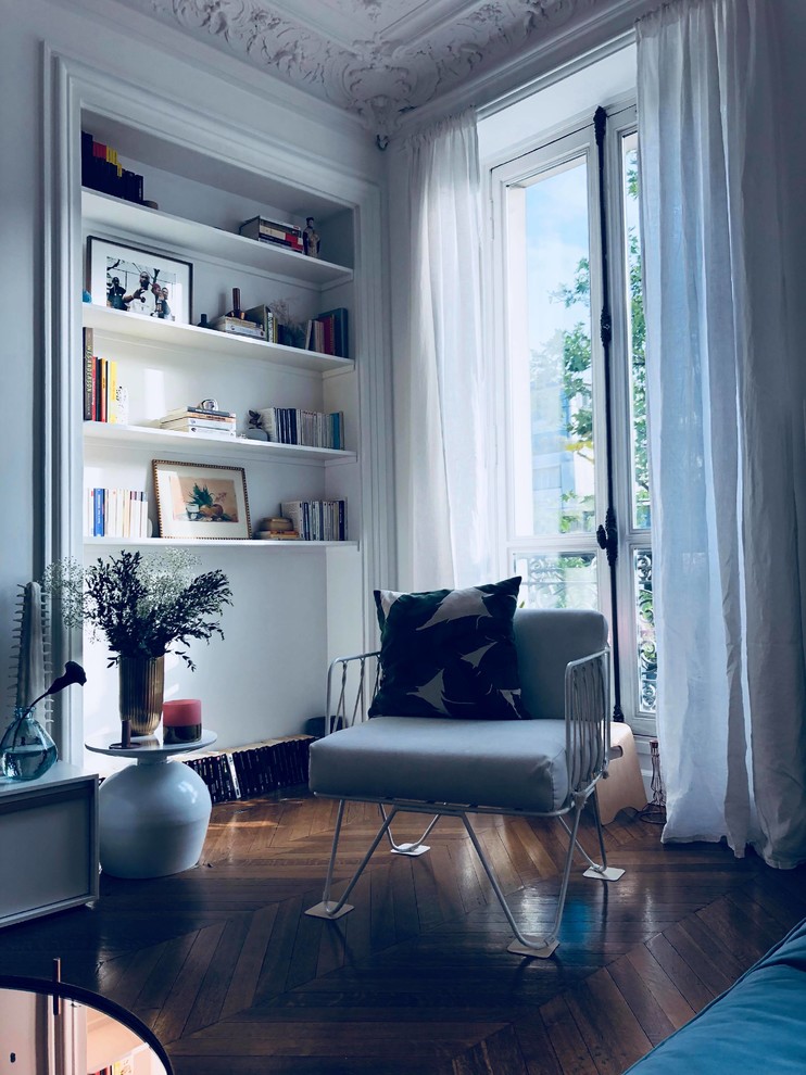 Immagine di un soggiorno design di medie dimensioni e chiuso con libreria, pareti bianche, pavimento in legno massello medio e pavimento marrone