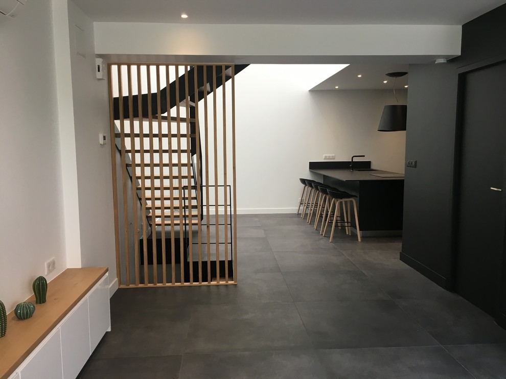 Immagine di un soggiorno minimal di medie dimensioni e aperto con pareti bianche, pavimento con piastrelle in ceramica, TV nascosta e pavimento nero